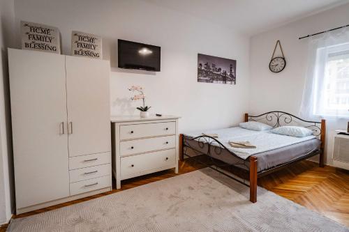 a bedroom with a bed and a dresser and a tv at LénApartman - Holiday in Pécs