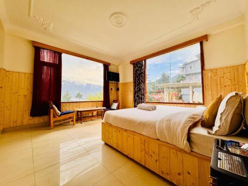 a bedroom with a bed and a large window at New Suraj Inn - Nestled near Hadimba Temple ! Rooftop Cafe ! Private Parking in Manāli