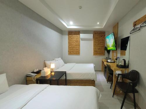 a hotel room with two beds and a desk at Orago Stay Hotel in Suwon