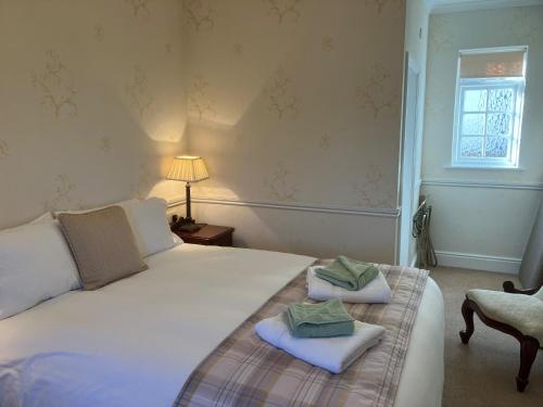 a bedroom with a large white bed with towels on it at Chapel House in Atherstone