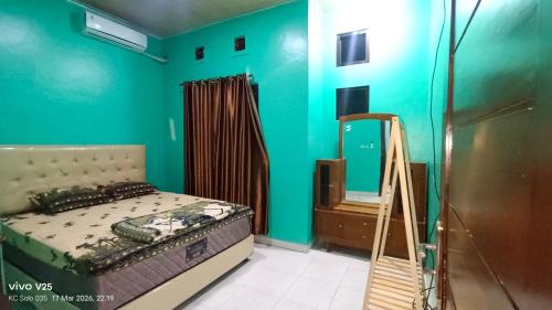 a bedroom with a bed and a green wall at Homestay Karimun in Grogol