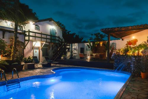 a swimming pool in front of a house at night at Casa Aldeia Paraty in Paraty