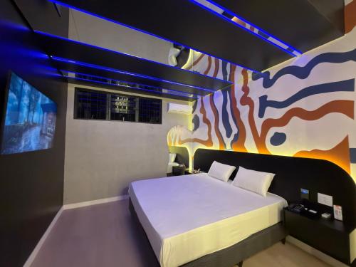 a bedroom with a bed with a painting on the wall at Blue Suítes - motel in Cascavel