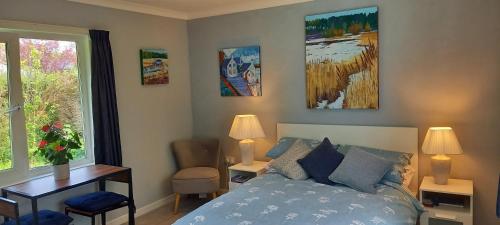 a bedroom with a bed and a desk and a window at The Annexe in Kirkcudbright