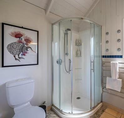 a bathroom with a shower and a white toilet at Hot Tub Seaview Chalet 12 in Waiheke Island