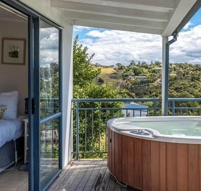 a jacuzzi tub on a balcony with a view at Hot Tub Seaview Chalet 12 in Waiheke Island