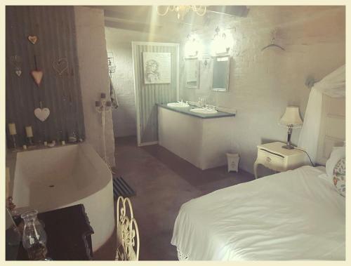 a bedroom with a tub and a bed and a sink at Die Woestynroos Gastehuis in Isidule
