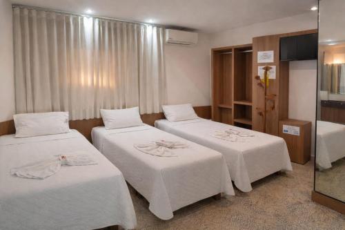 a hotel room with two beds with white sheets at Hotel Pousada Bortolan in Poços de Caldas