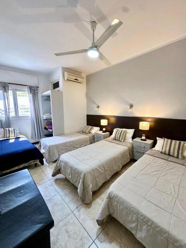a bedroom with three beds and a ceiling fan at Hotel Estrella Andina in San Juan