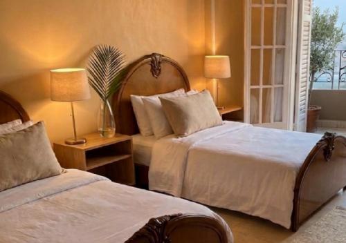 a bedroom with two beds and two tables with lamps at HK Pyramids Guest House Hospitality& Kindness in Cairo