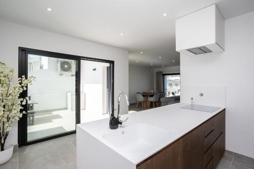 a kitchen with white countertops and a large window at Lusomare By Marenssa in Moncarapacho