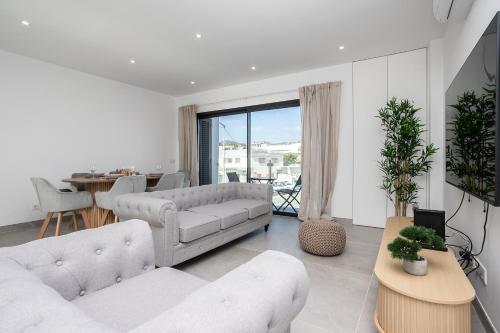 a living room with two white couches and a table at Lusomare By Marenssa in Moncarapacho