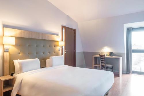 a bedroom with a large white bed and a desk at Kyriad Argenteuil in Argenteuil