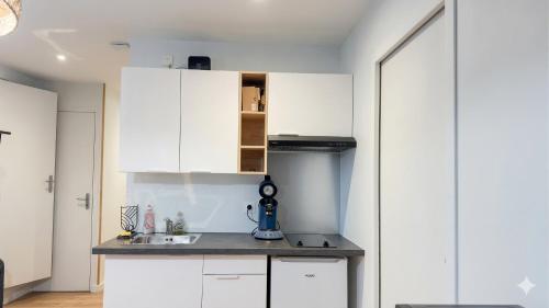 a kitchen with white cabinets and a sink at KENDALL in Saint Malo