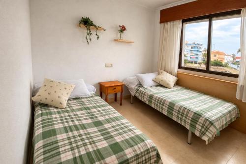 two beds in a room with a window at Apartamento en Xeraco in Xeraco