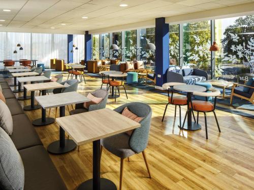 a restaurant with tables and chairs and windows at ibis budget London Heathrow Central in Hounslow