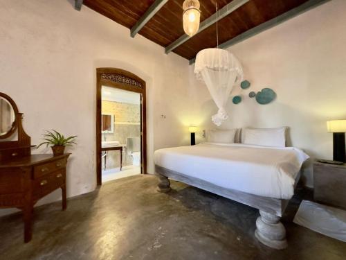 a bedroom with a bed and a table and a mirror at Foozoo Mantra Weligama in Weligama