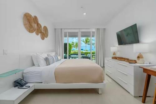 a white bedroom with a bed and a television at Apartment in paradise on the happy island of ARUBA, beachfront in Savaneta