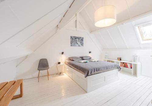 a white bedroom with a bed in a attic at Aalduiker 7 in Nieuwpoort
