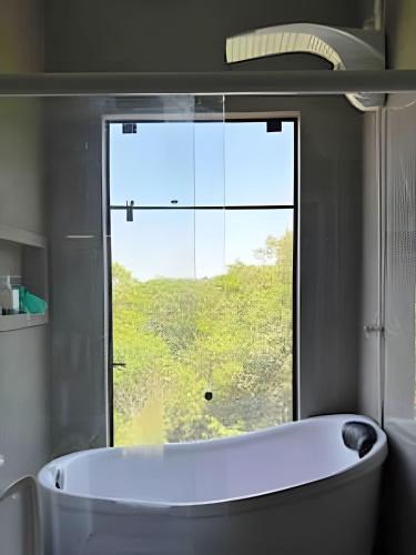 a bath tub in a bathroom with a window at Lakefront Chalet, hot tub, heated bathtub and waterfall in Alexânia