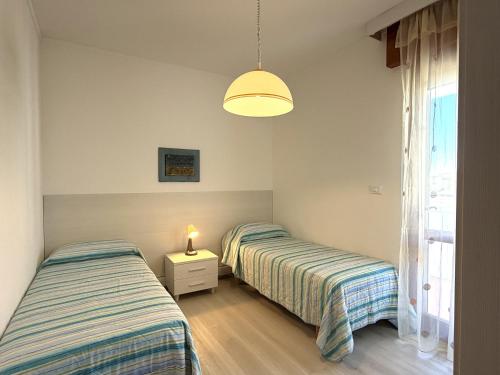 two beds in a room with a window at Appartamenti Oscar in Grado