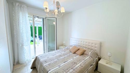 a white bedroom with a bed and a window at Villa singola con piscina Quinta Est in Rosolina