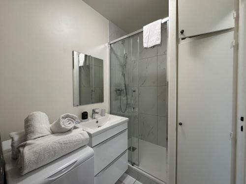 a white bathroom with a shower and a sink at Cosy studio centre-ville & RER A in Saint-Germain-en-Laye