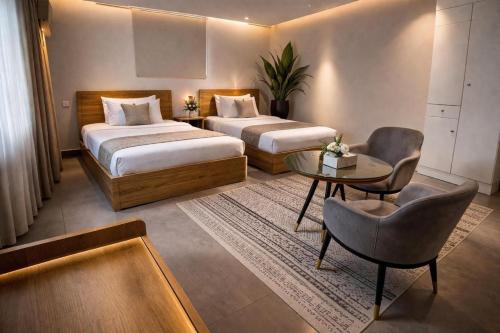 a hotel room with two beds and a table at Najd APARTMENTS in Al-ʿUla