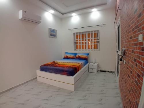 a bed in a white room with a brick wall at Continental in Komé