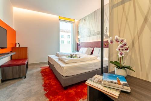 a hotel room with a bed and a table with a red rug at Campanile Venice Mestre in Mestre
