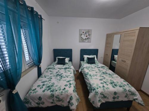 two beds in a room with blue curtains at Apartment Angel in Kotor