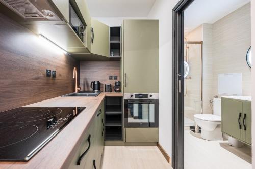 a kitchen with green cabinets and a toilet in a bathroom at Le Belmondo Grand Studio in Moutiers