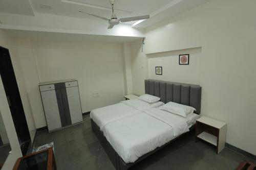 a bedroom with a large bed with white sheets at Hotel Keshav Pride in Dhule