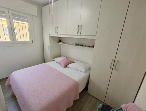 a bedroom with a pink bed and white cabinets at Piazzetta 293 in Rosolina Mare