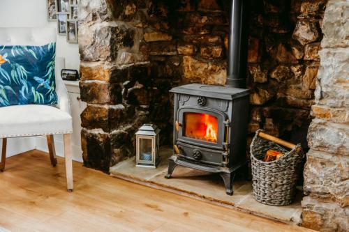 a wood stove in a living room with a chair at Pauls Place in Brynsiencyn