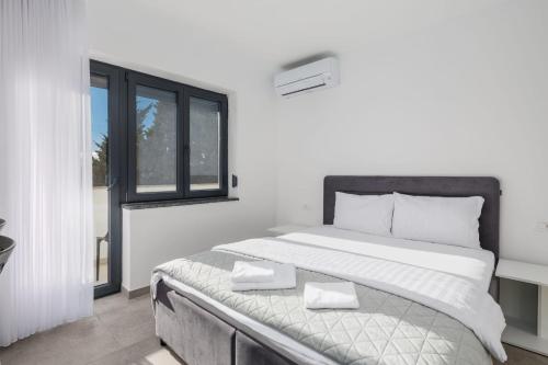 a white bedroom with a large bed and a window at Apartments Rea in Krk