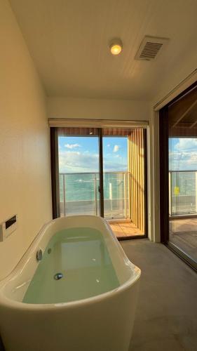 a bath tub in a room with a view of the ocean at Laina Kai in Sumoto