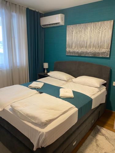 a bedroom with two beds and a blue wall at Zlatibor Royal Centar Lux in Zlatibor