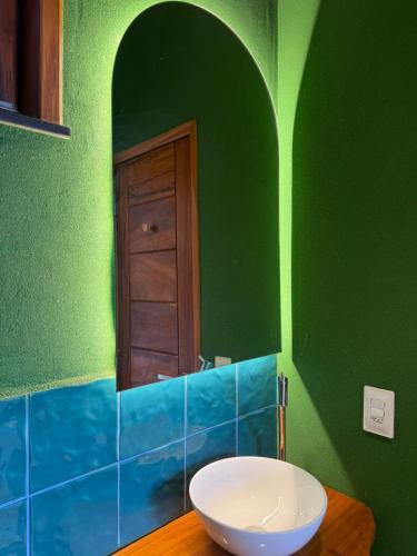 a bathroom with a sink and a green wall at Casa Floratta - Flecheiras in Flecheiras