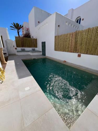 a swimming pool in front of a house at Dar Lisa - Charming authentic beachfront villa in Aghīr