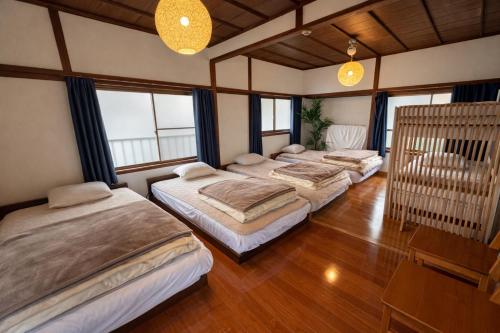 a group of four beds in a room with windows at Inasa Worlds Top Night View Retreat稲佐パノラマ夜景1棟貸切 in Nagasaki