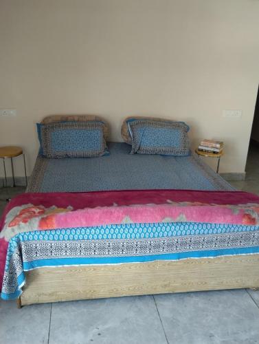 a wooden bed with a colorful blanket on it at Leisure Paradise in Kharar