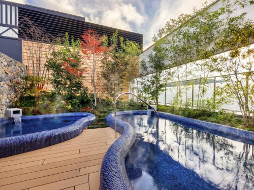 a swimming pool with two jacuzzis in a garden at Mercure Hida Takayama in Takayama