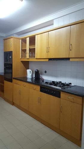 a kitchen with wooden cabinets and a stove top oven at Apartamento Vista Deslumbrante in Ponta Delgada