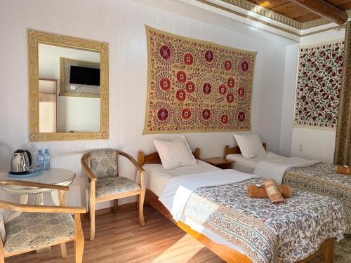 a room with two beds and a table and a mirror at Samani Bukhara in Bukhara