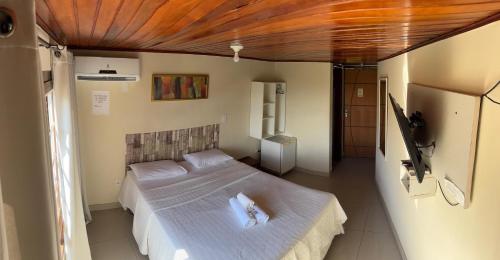 a bedroom with a large bed with white sheets at Suíte Atobás in Arraial do Cabo