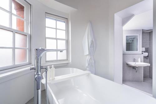 a white bathroom with a tub and a sink at The Jubilee by Supercity Aparthotels in Leeds