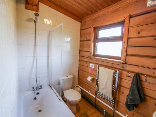 a bathroom with a tub and a toilet and a window at Primrose Lodge in Evesham