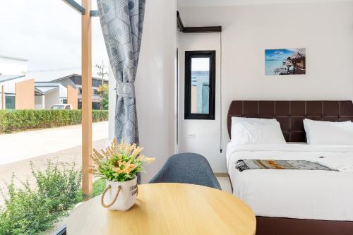 a room with a bed and a table and a bed and a window at Deluxe Hotel Chaiyaphum in Chaiyaphum