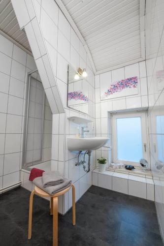 a white bathroom with a sink and a chair at Pension Onken in Bockhorn